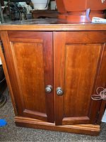 Front view showing double cabinet doors with metal knobs and wood paneling.
