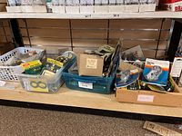 Various bins containing packaged house numbers, door locks, and assorted hardware items on store shelves.