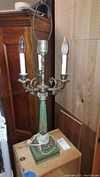Full view of the lamp showing metal candelabra style arms with candle bulbs and green decorative metal base with crystal accents.