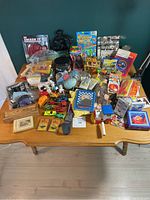 Full view of assorted vintage toys arranged on a wooden table including packages and loose toys