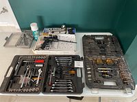 Top-down overview of multiple tool sets including screwdrivers, socket wrenches, and drill bits in their cases and boxes