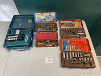 Photo showing the four metal socket sets and the Makita cordless driver drill in blue metal case