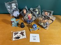 Overview of 11 Star Wars collectible toys mostly in plastic packaging on a table against a teal wall