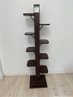 Full view of antique eight-tier plant stand showing vertical wooden support and tiered shelves.