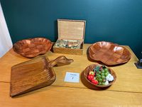 Wide shot of all five wooden items including the vintage puzzle box, two apple-shaped trays, decorative bowl with faux fruit, and the carved wooden duck-handled dustpan on a wooden surface.