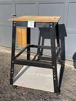 Full view of metal frame work stand with wooden top and bottom shelf on casters.