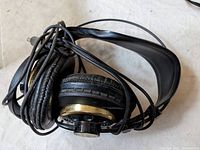Full view of the AKG headphones showing coiled black wire, ear pads with wear, and metal frame