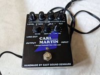 Top view of the Carl Martin pre-amp pedal showing six control knobs and text indicating handmade by East Sound Denmark.