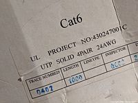 Close-up of the label showing product details: Cat6, UL listed, project number 430247001C, UTP solid 4-pair 24AWG, 1000 feet length.
