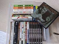 Top view of DVDs and audiobooks including Rear Window DVD, Vinyl Cafe audiobook volumes by Stuart McLean, Domino the Holidays audiobook, and Planet Earth DVD set.