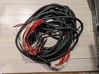 A coiled thick black 24 channel audio snake with multiple red and white wired leads at one end.