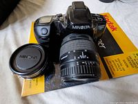 Minolta Maxxum 430si RZ camera with zoom lens attached, teleconverter lens beside it, Kodak picture paper under camera