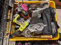 Orange and pink tools with hand gloves and safety goggles in a yellow container.