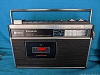 Front view of Silver RT 31 shortwave radio cassette recorder showing cassette slot, radio tuning meter, and frequency dial.