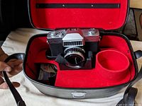 Agfa Kamara camera in black hard case with red felt interior, showing front and side view of camera and part of case.