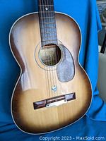 Front view of the Suzuki No 7 acoustic guitar showing the sunburst finish, pickguard, and steel strings.