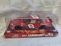 Front and side view of the sealed Dale Earnhardt Jr. #8 red NASCAR stock car model with packaging and display case.