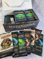 Opened box showing multiple Magic: The Gathering Tenth Edition Core Set booster packs with varied artwork.