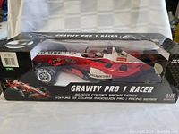 Front angled view of the Gravity Pro 1 Racer remote control race car in its original box showing the red and white racing design and branding.