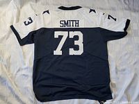 Back view of the navy blue and white Dallas Cowboys football jersey showing number 73 and name SMITH.