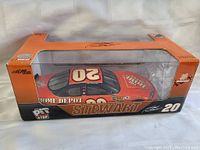 Front and side view of Tony Stewart NASCAR diecast model car in original box showing number 20 and Home Depot sponsor