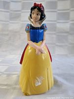 Front view of Snow White figurine showing damage on yellow skirt.