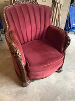 Full front view of the antique occasional chair showing deep red plush upholstery and high backrest with vertical channel tufting.