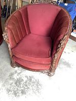Front view of antique armchair showing red plush upholstery and carved wooden arms with love bird motifs.