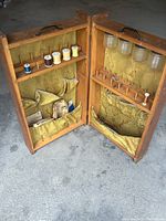 Open view of antique wooden sewing box with multiple thread spools and storage compartments lined in green fabric.