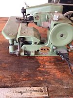 Side view showing full machine body, handwheel, needle arm, and base stamped with brand and model info.