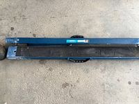 Top view of two blue metal folding sawhorses laid flat, showing handle and protective black rubber/plastic tops.