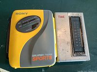 Front view of Sony Walkman FM/AM Sports and small transistor radio showing controls and brand markings