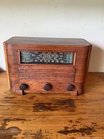 Front view of vintage General Electric tube radio showing wooden cabinet, tuning window, and three control knobs.