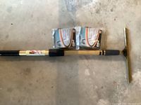 Full length view of adjustable window wiper pole laid on a concrete floor with two new wiper blades above it