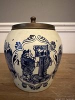 Full view of cylindrical Delfts humidor showing traditional blue and white painted scene and pewter lid.