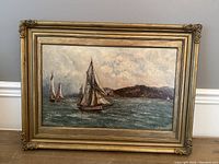 Full view of the framed oil painting showing seascape with ships and detailed frame.