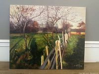 Front view of signed oil painting depicting fenced landscape with trees and building under cloudy sky.