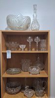 Wide view of bookshelf with assorted crystal glassware including bowls, decanter, tumblers, stemware, and ice bucket