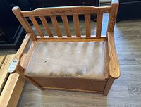 Front view of wooden hall bench showing cushioned seat with light stains and carved floral detail on backrest.