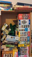 Photo showing various boxed puzzles and games including Multi Art Collections puzzles with piece counts from 500 to 1000, Roll & Play game, and green fabric bag.