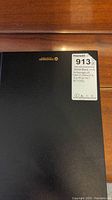 Photo of black sketchbook cover with MaxSold auction label indicating original signed comic drawings inside.