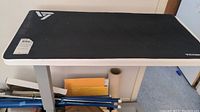 Photo showing top surface of the adjustable work station with black tabletop and brand label visible.