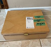 Closed wooden box containing the chess set with green tape labeling it as Chess Set.