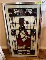 Full frontal image of glass wall art with a woman and floral design in a silver frame.