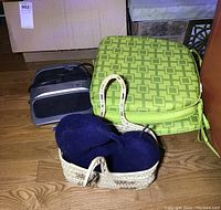 Photo of Homedics foot massager, green patterned seat cushions, navy blue neck cushion, and woven basket on wooden floor.