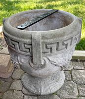 Front angled view of the concrete urn showing Greek dental pattern and grape relief, with ruler across the top indicating size.