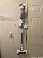 Full frontal view of the Tineco VA112000CA stick vacuum cleaner hanging on wall mount.