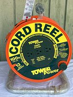 Front view showing the Tower Power branding, 100ft cord length, 3 grounded outlets, and power specifications.