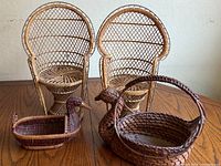 Two miniature queen chairs side by side with two duck-shaped baskets in front on a wooden table