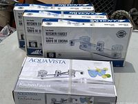 Four sealed kitchen faucet kits grouped, three Glacier Bay and one Aqua Vista model.